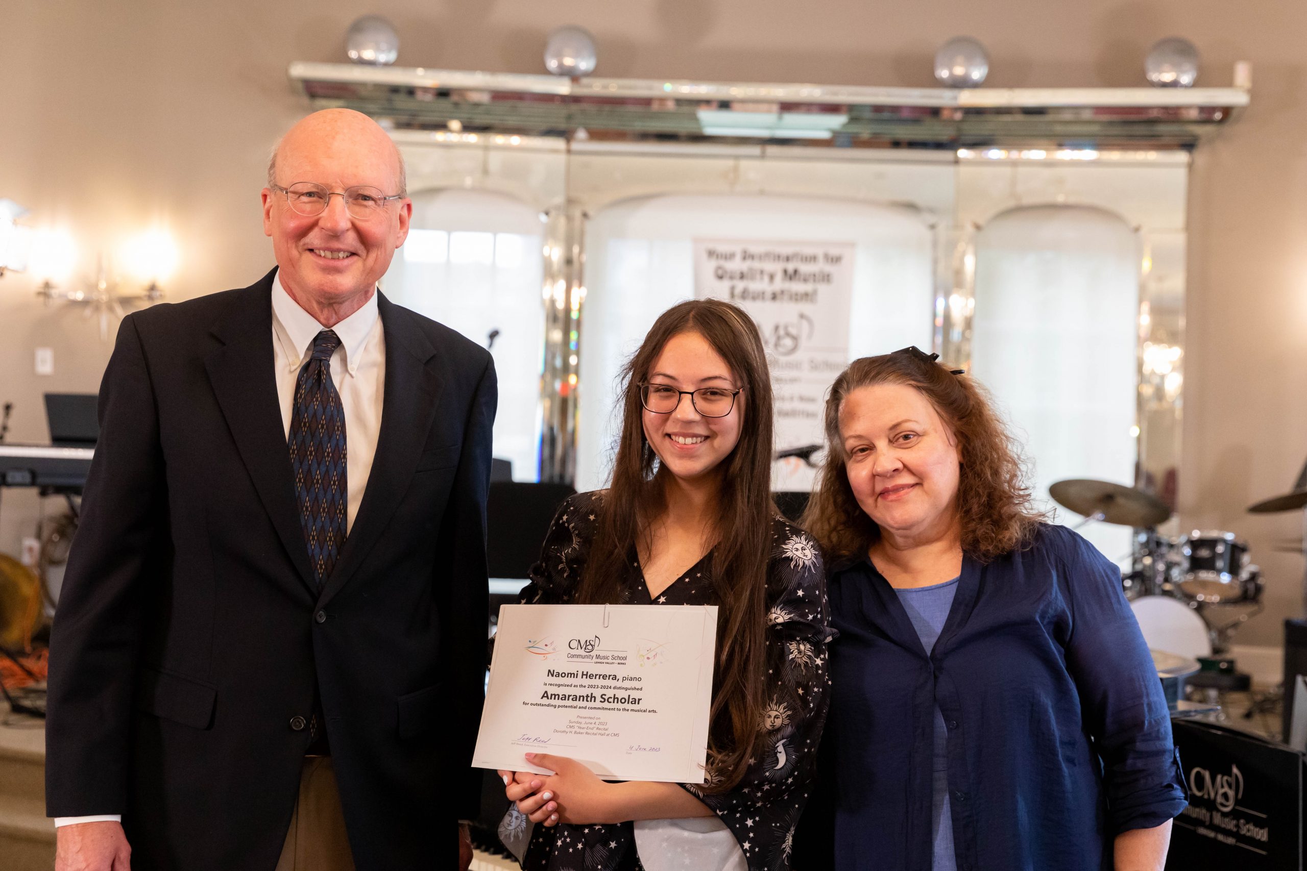 Naomi Herrera (center) was also recognized as the 2023-24 Amaranth Scholar for her outstanding dedication to her studies in piano, violin, and voice, here at CMS. Also pictured are Executive Director Jeff Reed (left), and Naomi’s piano teacher, Kathy Anthony (right). The Amaranth Foundation Scholarship is awarded to a CMS student who demonstrates a high potential for achieving excellence in music education and whose family has documented financial need. The Amaranth Foundation was founded by Joan Miller Moran and supports arts-related programming and organizations, including Community Music School.