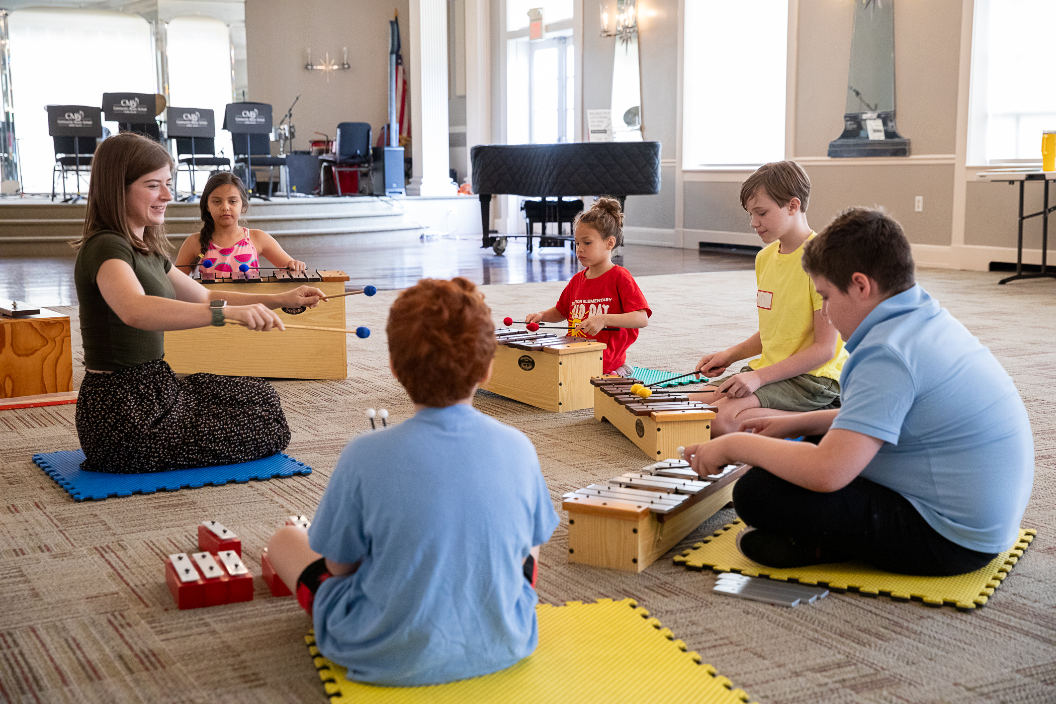 A group of young students listen intently to teacher Kelly Hooper during a group piano class at Community Music School.