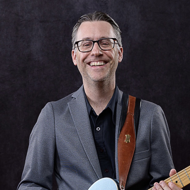 Andrew Portz headshot with guitar - teacher of guitar | bass guitar | ukulele | banjo | mandolin | piano